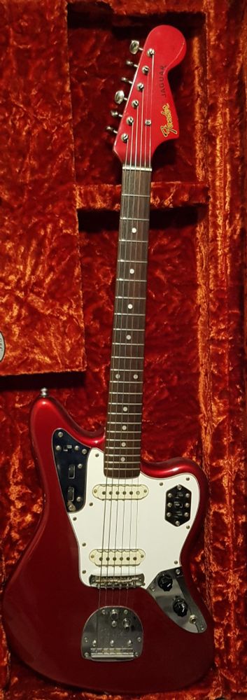 A Candy Apple Red Fender Jaguar rests in a red velvet-lined case, waiting for me to set it up. 