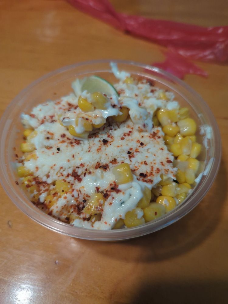A small to go container filled with roasted corn smothered in mayo, cheese, spices and lime.  Nomnomnomnomnom