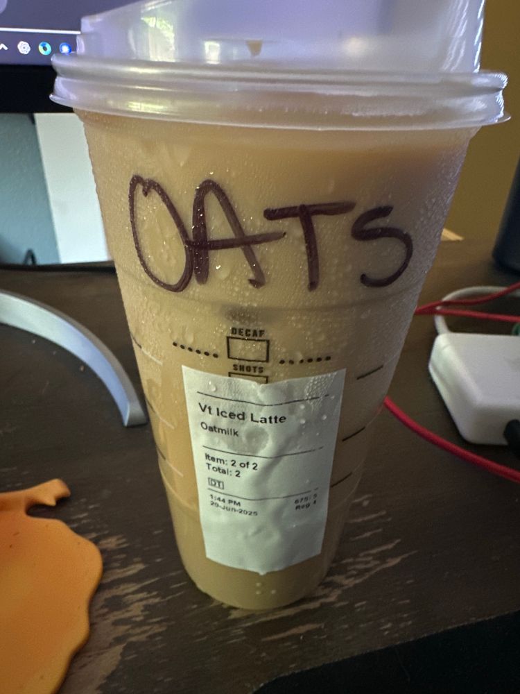 Starbucks iced Venti oat milk latte with the word OATS written in sharpie