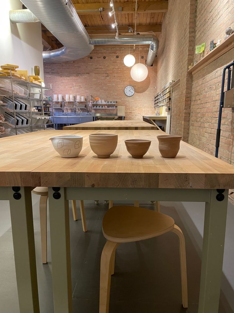 Four vessels lined up on a table in a studio. 