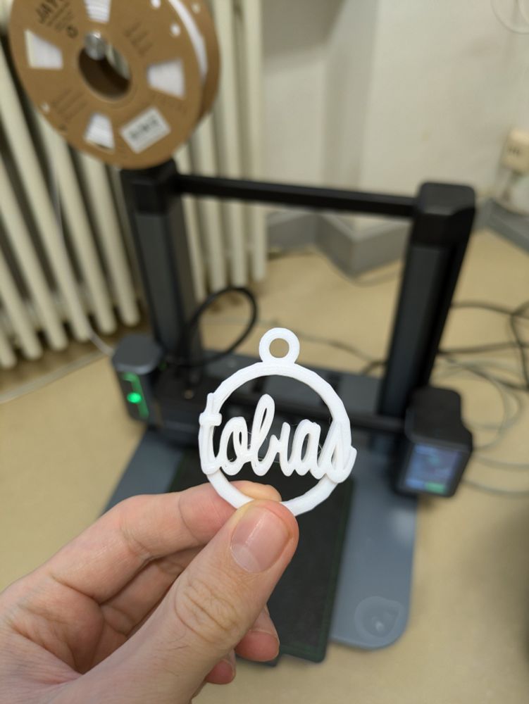 Ein fertiger Anhänger in Form einer 2D-Weihnachtskugel mit dem Namen Tobias darin.
