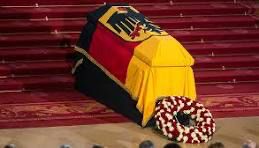 Sarg mit BRD Fahne drapiert und blumenkranz.