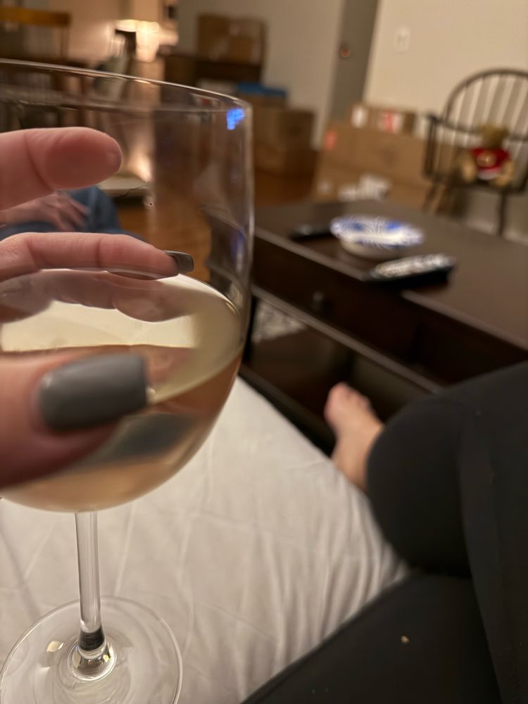 Holding a glass of wine with unpacked boxes in background 