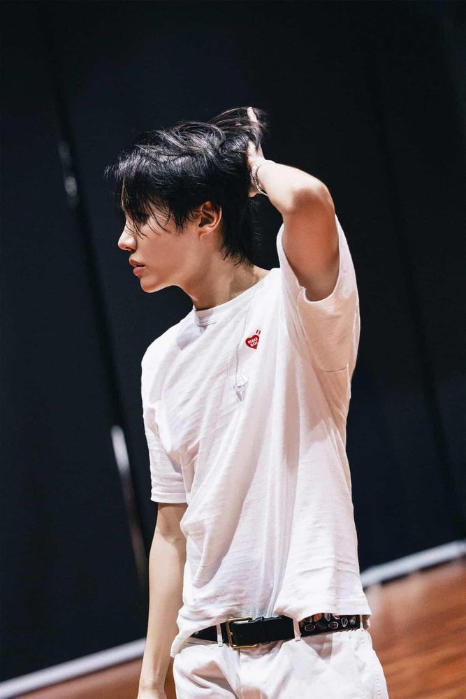 Side profile of Jung Hoseok with one hand in his hair, wearing a white tshirt and white jeans