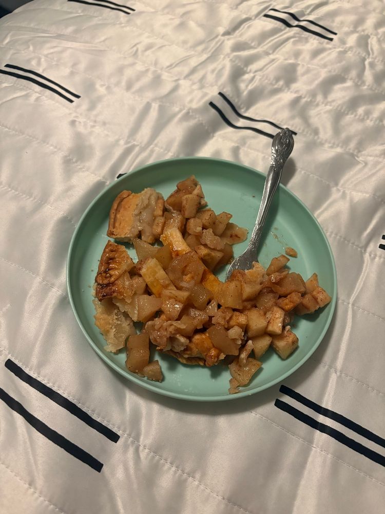 the jumbled remains of a piece of apple pie on a small seafoam plate