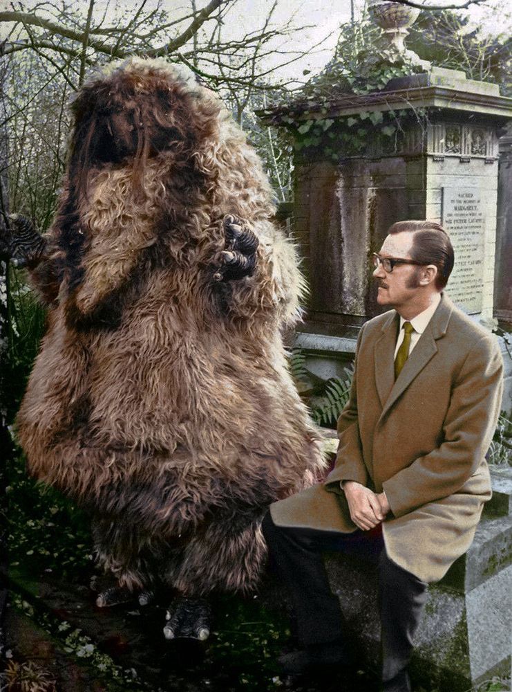 A Yeti from Doctor Who, stood next to Alan Whicker, next to each other in a cemetery.