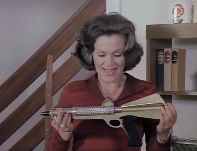 A Medusan woman looking at a gun with an expression bordering on ecstasy.