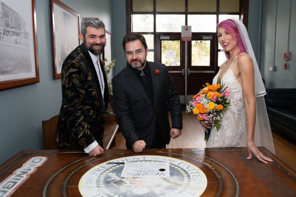 Jason, Phil and Alyssa signing the wedding certificate on the President’s desk from Idiocracy.