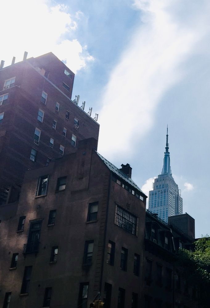 The image shows the Empire State Building behind other smaller buildings.