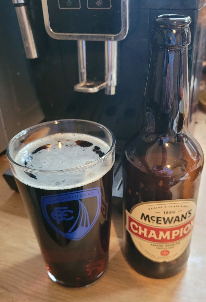 A pint pot with the Chesterfield FC crest full of dark ale, the bottle next to it has CHAMPION on it.