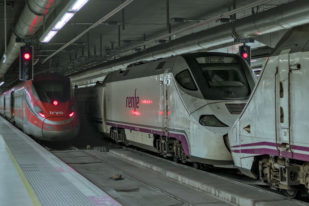 Two Renfe s/130s and an iryo s/109 train in Barcelona-Sants station