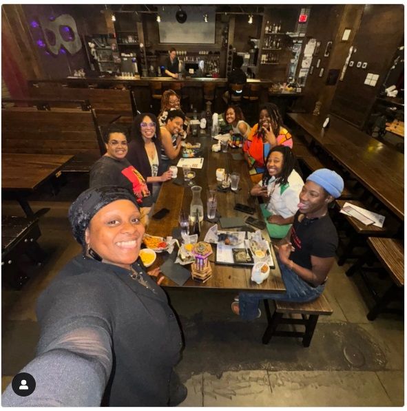 Nice beautiful people gathered around a long wooden table at a gastropub