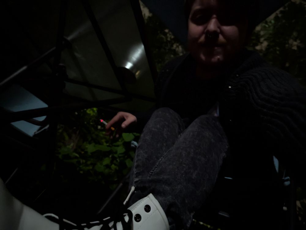 Dark photo of fox leaning over and looking down at you from his boots level. His boots are white and he holds a lot cigarette 