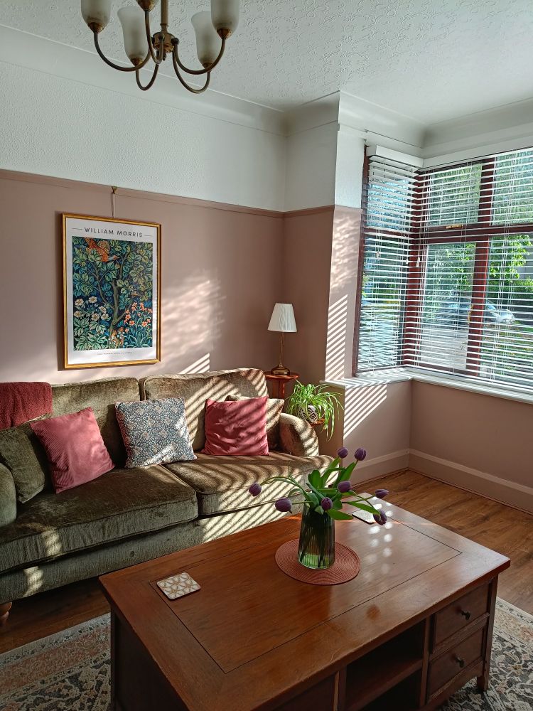 Modern vintage living room with green sofa, pink walls and a wooden coffee table