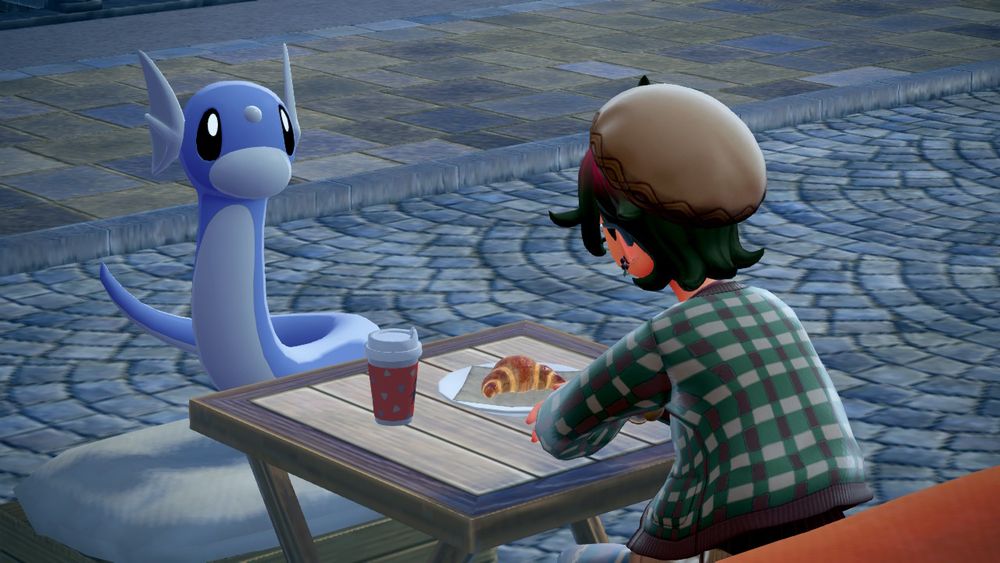 screenshot of a dratini sitting across from a pokemon trainer having a coffee and a croissant. they are looking at the trainer. 