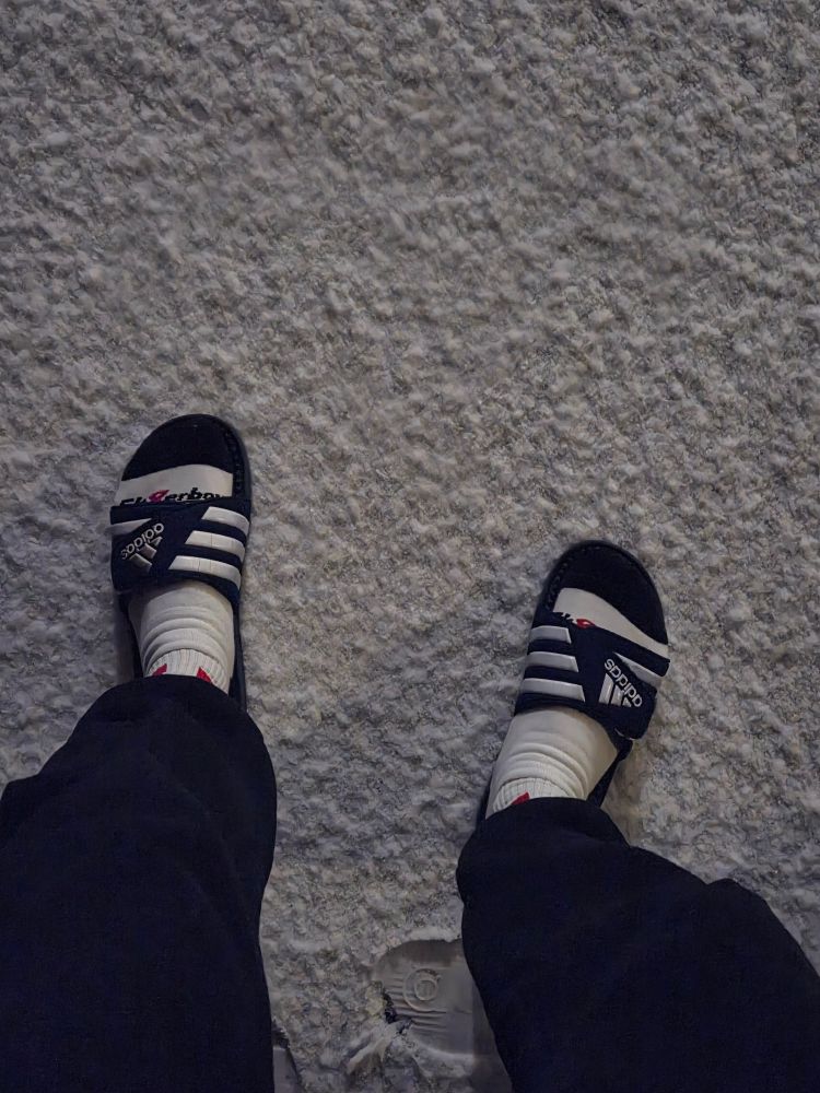 Blick an meine Beine runter in schwarzer sweatpants mit adidas Schlappen und weiße Socken

ich stehe auf frisch beschneitem Weg