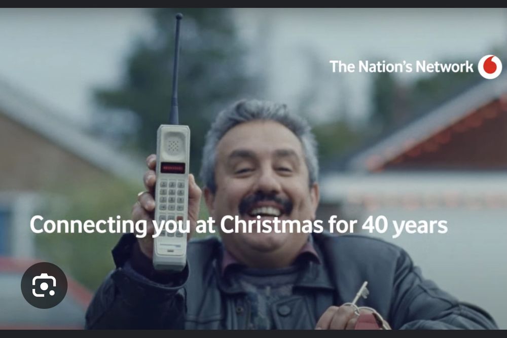 A still from a Vodafone tv ad, a man from the 1980s holds up his first ever mobile