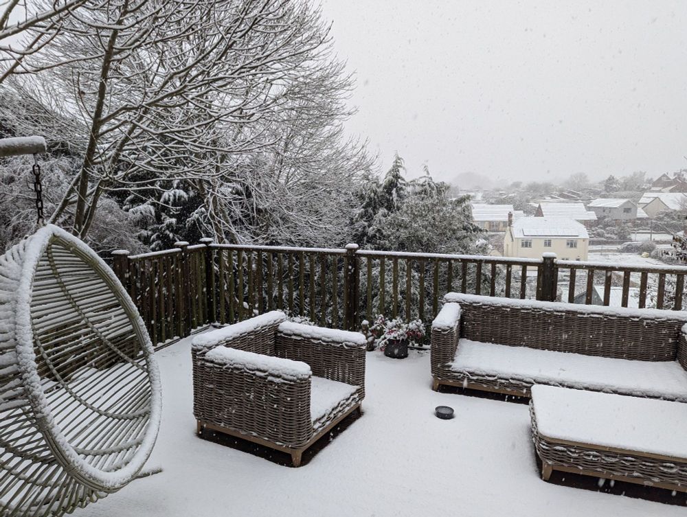 Snowy view of a town. Decking, roofs and trees covered with an inch of snow.