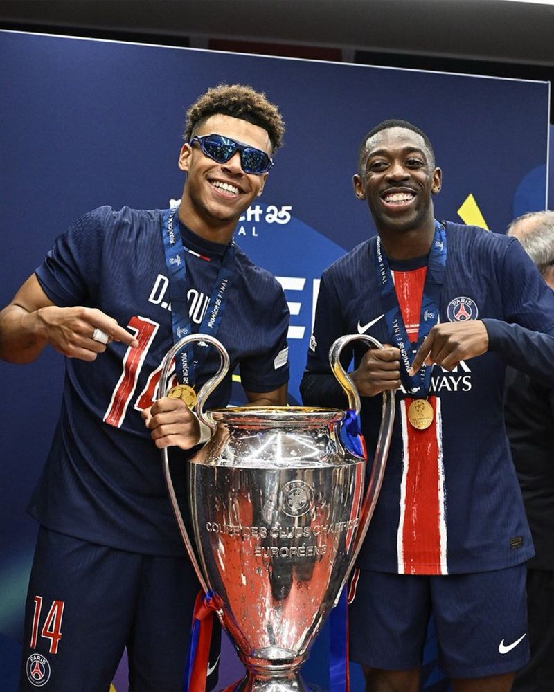 Désiré Doué (avec de magnifiques lunettes de soleil) et le futur ballon d’or Ousmane Dembélé tenant la coupe de la Ligue des Champions après que le plus grand club de France, le Paris Saint Germain, ait humilié l’Inter Milan 5-0 en finale 