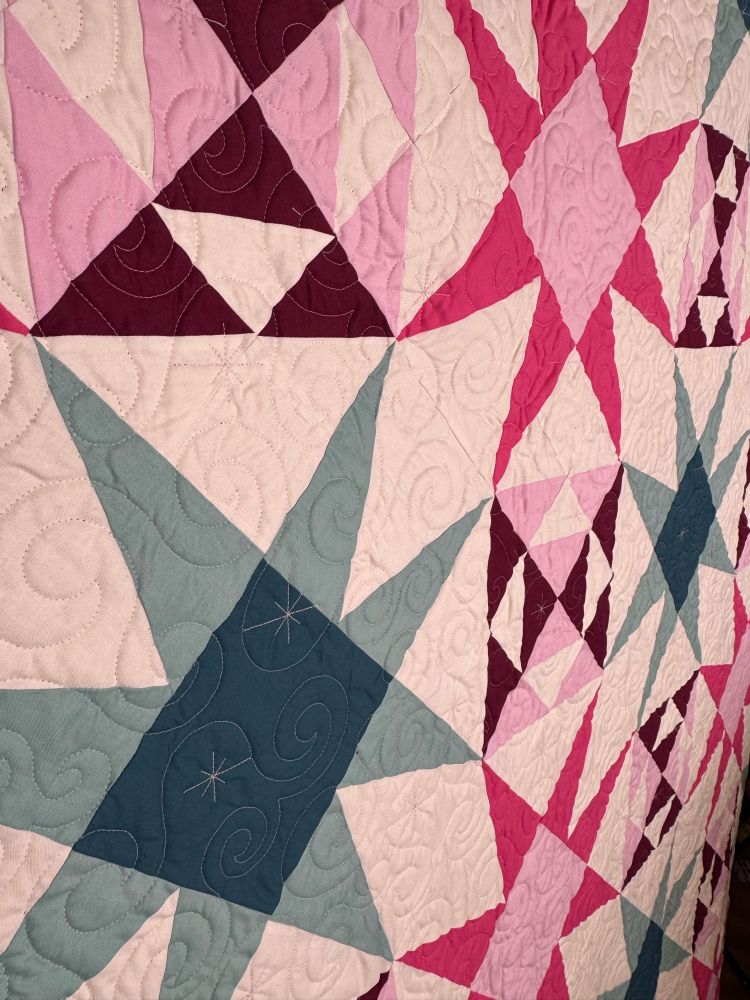 Zoom in on quilt to see the quilting up close.  Swirly quilting over star shaped piecing