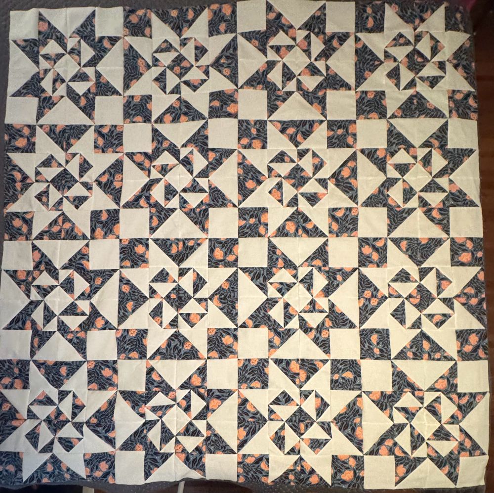 Inverted stars in a 4x4 grid. Each star’s center are rotated flying geese creating a pinwheel effect.