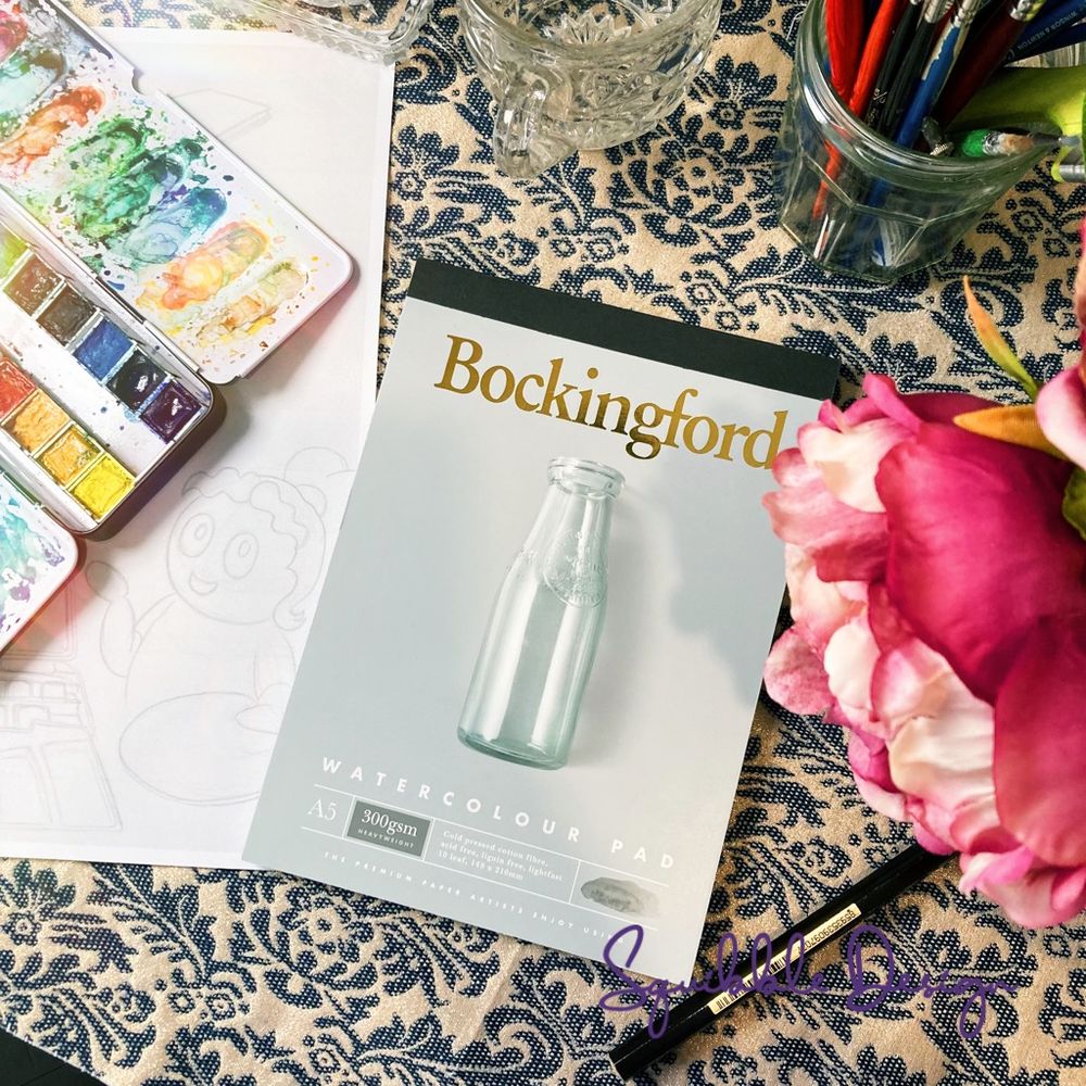 Photo of a new watercolour pad on my desk next to a scan of my sketchbook drawing and my watercolour palette.