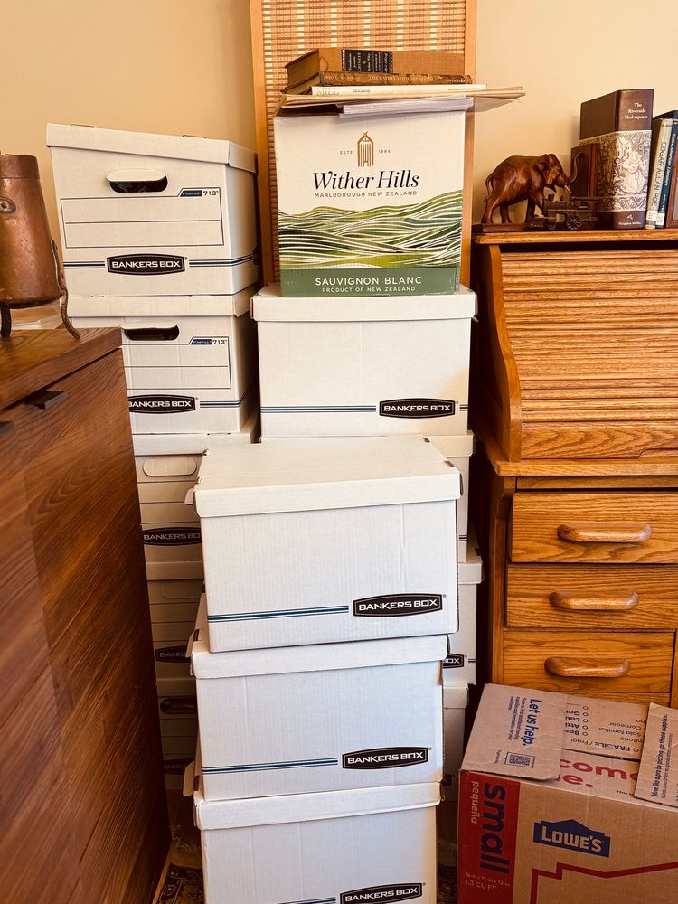 White bankers boxes stacked on too of each other, filled with books.