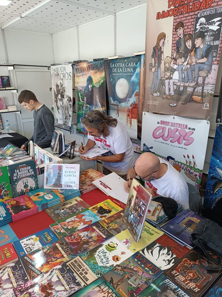 El guionista Eliseo García y el dibujante Javier Urrea firmando ejemplares de su cómic "Días dw inmortalidad" en la caseta de la editorial Drakul en la feria del libro de Alcalá de Henares.