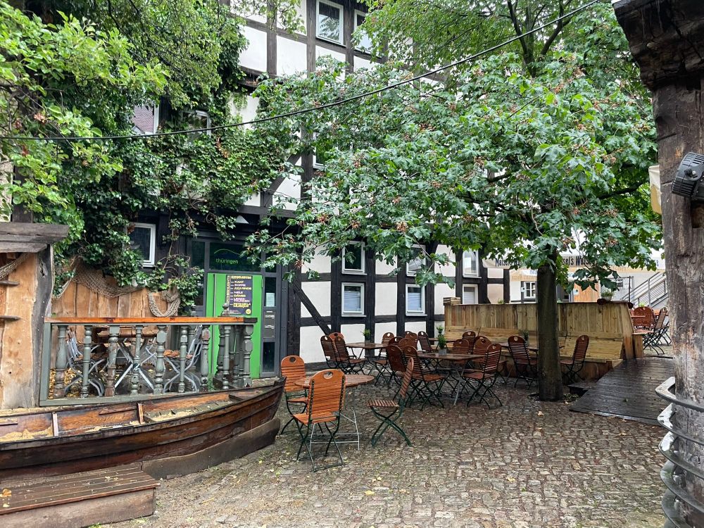 A courtyard showing cobbles and trees and a half-timbered facade.
