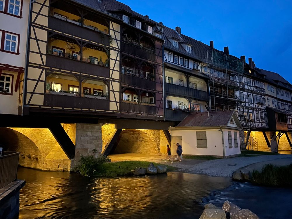 Covered medieval bridge in the evening with four-storey buildings overlooking the water below
