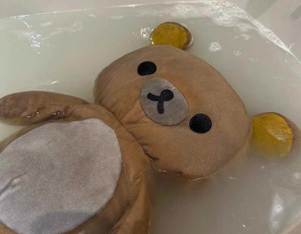 une grosse peluche nounours brune, qui est sur le dos dans un bain. Elle a clairement l'air au bout de sa vie et ne semble pas être en train de se relaxer, mais plutôt de remettre en cause tous ses choix de vie.