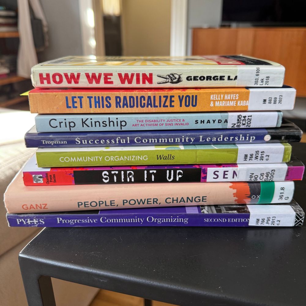 Pile of books on a black metal table. Titles (from top to bottom) are:

How we win : a guide to nonviolent direct action campaigning by George 
Lakey. 

Let this radicalize you : organizing and the revolution of reciprocal care by Kelly Hayes.

Crip kinship : the disability justice & art activism of Sins Invalid by Shayda Kafai 

Successful community leadership : a skills guide for volunteers and professionals by John E. Tropman

Community organizing : fanning the flame of democracy by David S. 
Walls.

Stir it up : lessons in community organizing and advocacy by Rinku 
Sen.

People, power, change : organizing for democratic renewal by Marshall Ganz.

Progressive community organizing : reflective practice in a globalizing world
by Loretta Pyles. 

