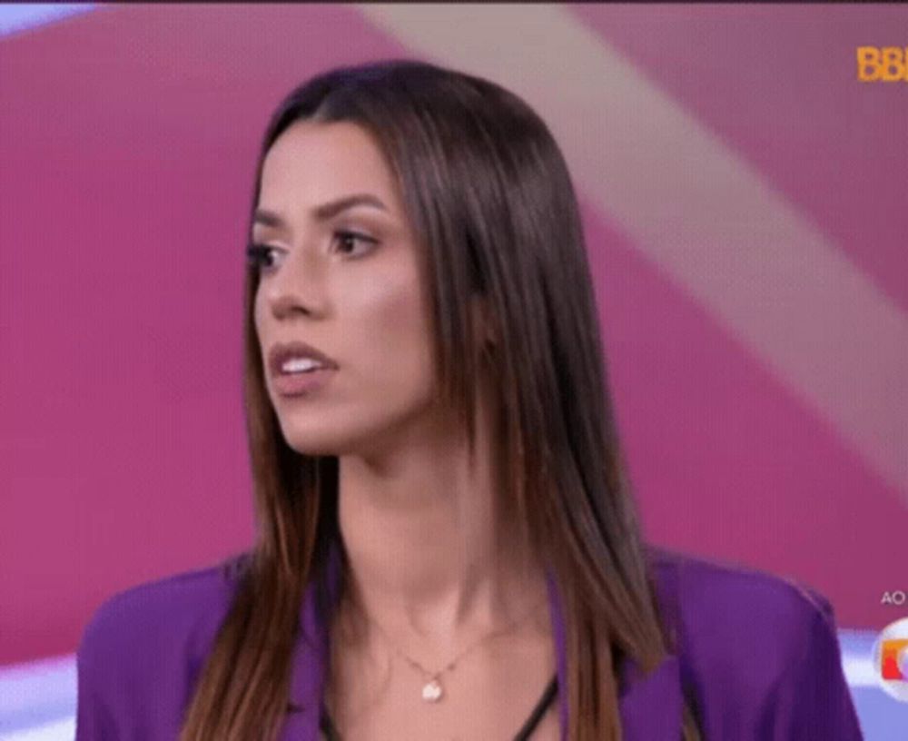 a woman wearing a purple jacket and necklace is looking at the camera .