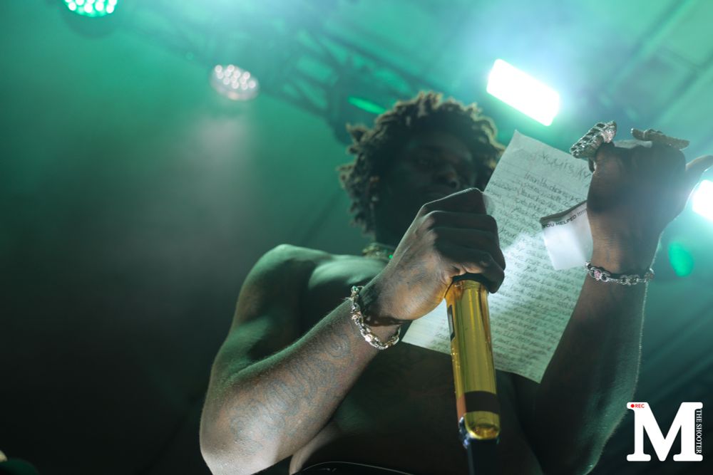 Kodak Black holding a microphone and reading a fan letter. 