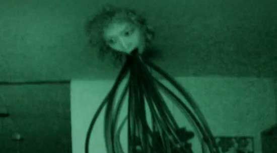 Scene from Kōji Shiraishi's Cult (2013) of a tentacle-spewing face pushing through the ceiling of some poor sod's home.