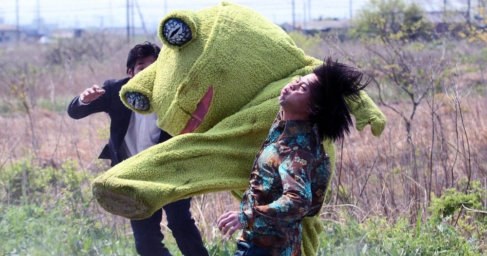 Scene from Takashi Miike's Yakuza Apocalypse (2015) of someone in a frog mascot outfit kicking the shit out of a pair of fools.