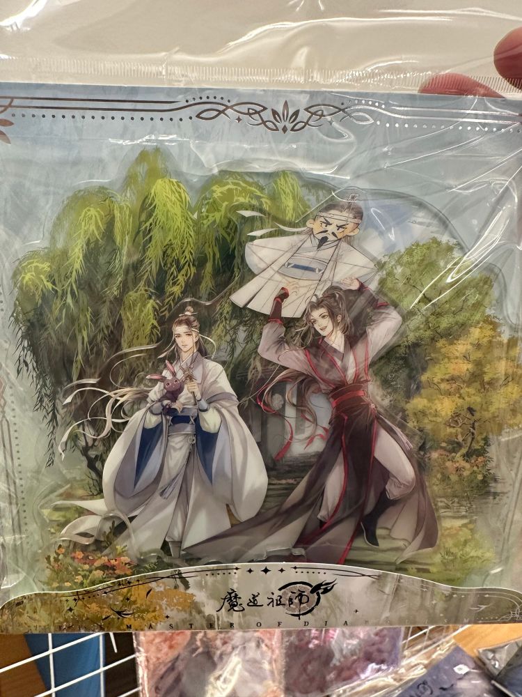 Acrylic standee featuring wangxian in the donghua Gusu lectures era outfits. Lan Wangji is holding a black bunny, Wei Wuxian is holding a kite that looks like an angry Lan Qiren