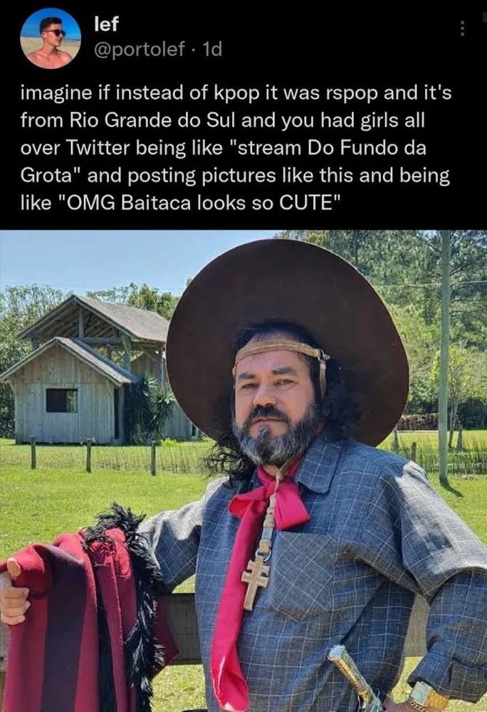 um post em inglês no falecido X falando "imagine if instead of kpop it was rspop and it's from Rio Grande do Sul and you had girls all over Twitter being like "stream Do Fundo da Grota" and posting pictures like this and being like "OMG Baitaca looks so CUTE"" com uma foto do Baitaca escorado em uma cerca no campo, com uma casa de madeira ao fundo e algumas arvores. o dia desta foto está ensolarado, céu límpido. Baitaca usa um chapéu que o diâmetro chega a 3 vezes sua cabeça, usa uma camisa cinza médio com uma textura xadrez de baixo contraste, um lenço vermelho que vai quase na altura do seu umbigo, uma cruz missioneira feita aparentemente de madeira e ele segura um pala vermelho rubro em seu braço direito, seu braço esquerdo está apoiado na cintura de onde podemos ver também a empunhadura de metal de sua faca. Baitaca é um homem branco na casa de seus 50 a 60 anos, cabelo comprido bem ondulado, barba cheia com traços grisalhos.