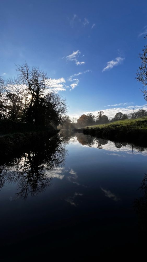 An autumnal morning with clear blue skies with mist rising up from the canal in the distance.