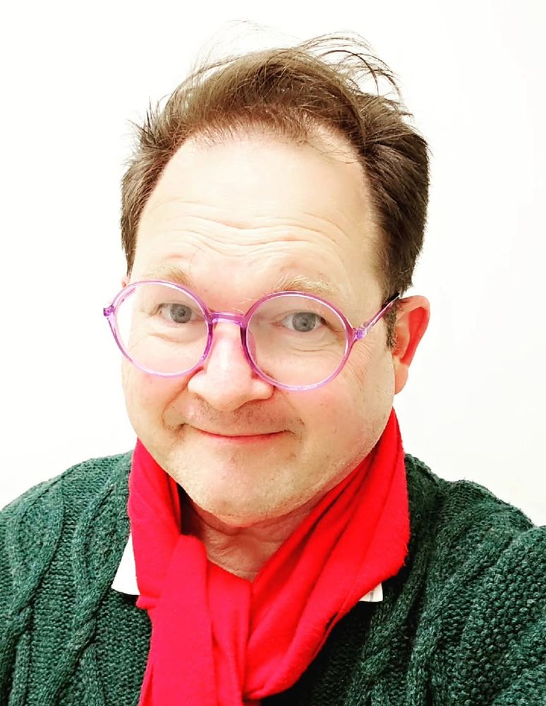 Me, smiling, wearing a green sweater and red scarf. 