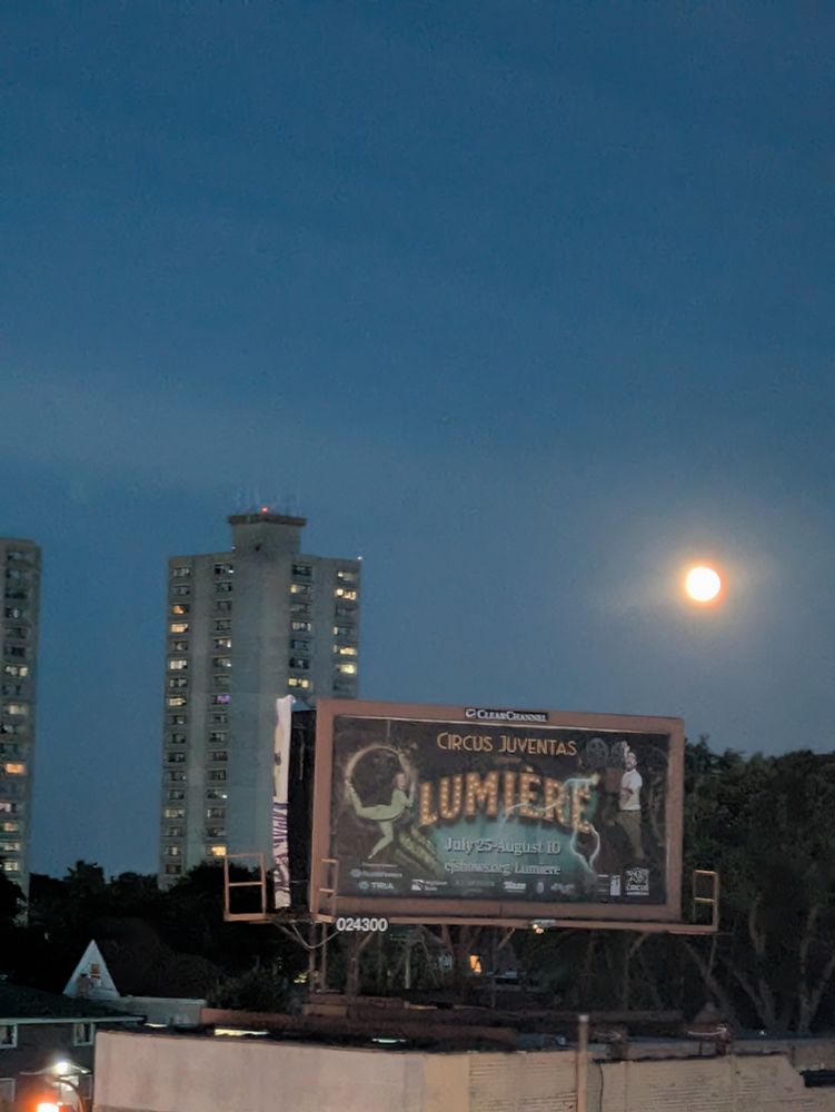Full Moon above a billboard that says Lumiere in fancy letters on a circus poster