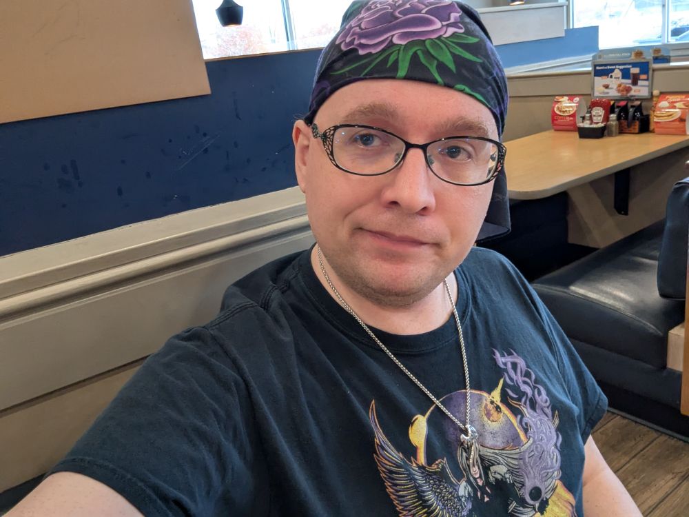 Fellwing himself, wearing a Sephiroth T-shirt, a wing necklace, and a purple rose bandana. 