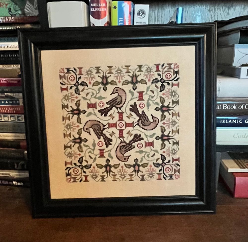 Cross stitch design with four birds, flowers, and spools of thread