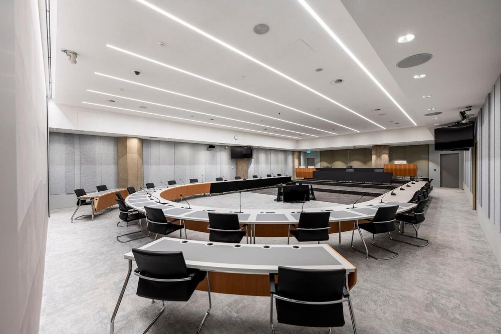 Een foto van de volledige Troelstrazaal van de Tweede Kamer met daarin tafels en stoelen. Er zijn geen personen aanwezig.