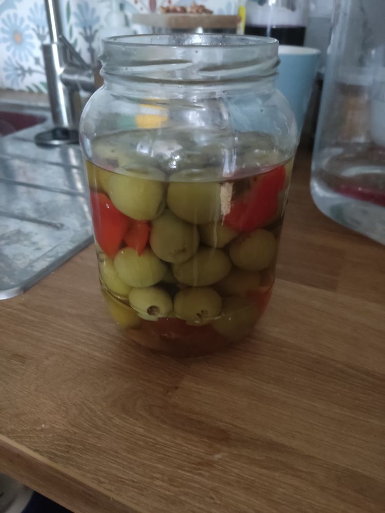 Słoik zielonych oliwek z papryką i czosnkiem na blacie kuchennym