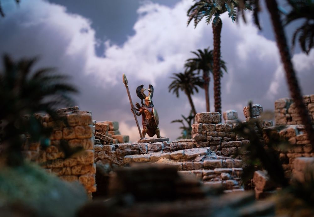 A Fenris Games Rubble City Adventurer and Rubble city scenery in front of a More Skies Backdrop Book.