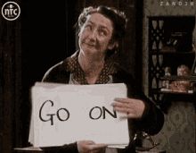 lady holding a sign that says "go on"