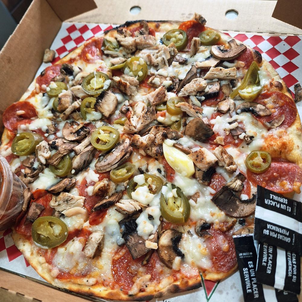 A pizza with grilled chicken, jalapeños, pepperoni, onion and mushrooms.