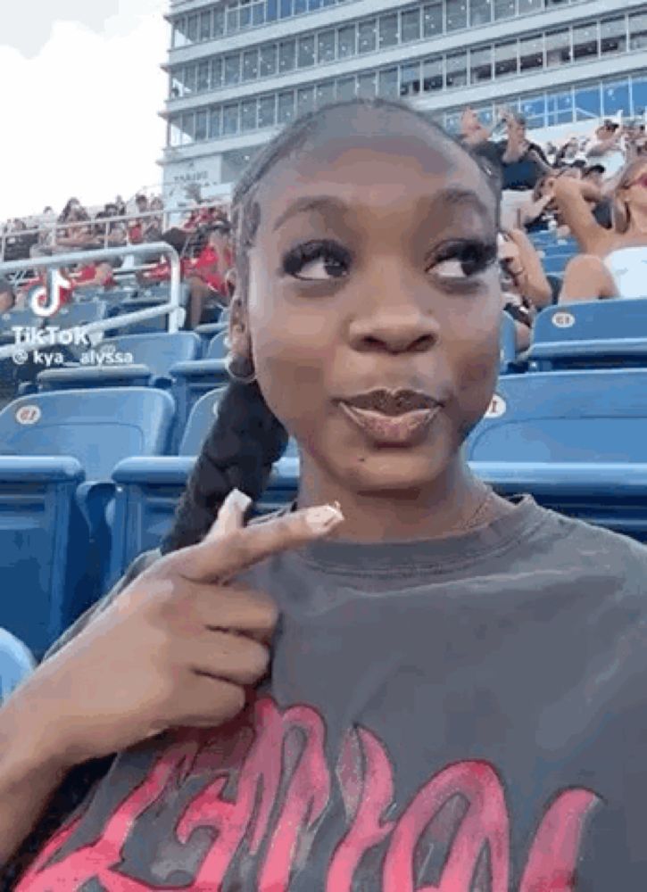 a woman is sitting in the stands of a baseball stadium .