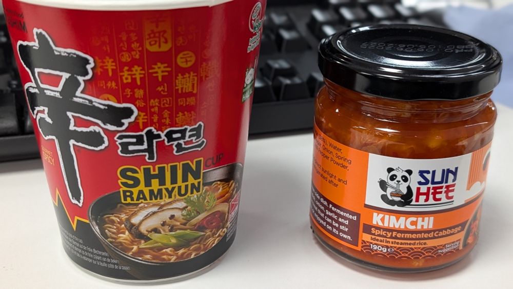 A Shim Rayun cup noodle alongside a jar of kimchi.